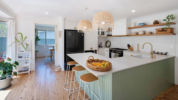 A modern kitchen with a large island, bar stools, pendant lights, and built-in shelves. - Luxurious & spacious retreat near Swan Lake (Sussex Inlet)
