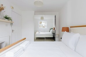 Ein Hotelzimmer mit Bett, Nachttisch, Lampe und Blick nach draußen.