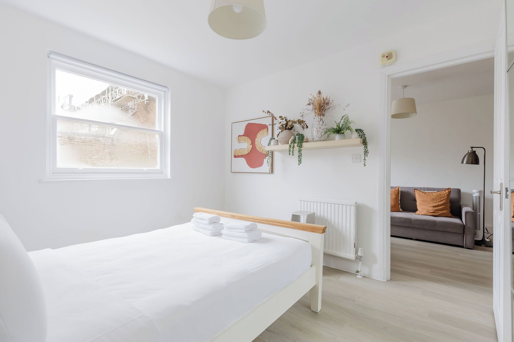 A modern bedroom with a bed, a radiator, a window, and a view of the outside.