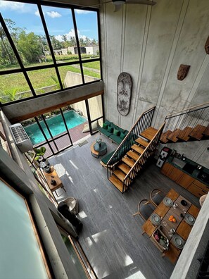 A spacious living area with a view of a swimming pool, a staircase, and a kitchen area. - Soothing 2-bedroom villa with AC in charming Ubud (UBUD)