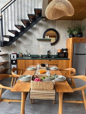 A modern kitchen with a wooden dining table set for four, a built-in stove, and a staircase with black railings. - Soothing 2-bedroom villa with AC in charming Ubud (UBUD)