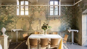 Una zona pranzo con pavimento a scacchi, un tavolo con sedie e un affresco sulla parete.