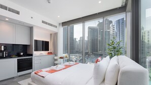 Une chambre moderne avec un grand lit, un coin cuisine et une vue sur la ville.