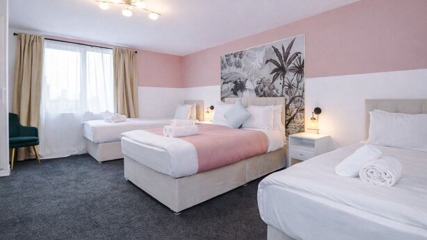 Habitación de hotel con dos camas, una silla verde, un cuadro grande y un ventilador de techo.