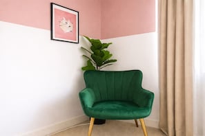 A green armchair in a corner with a plant beside it, a framed picture on the wall, and a beige curtain. - Budget Friendly Private Apartment - Free Parking (Salford)