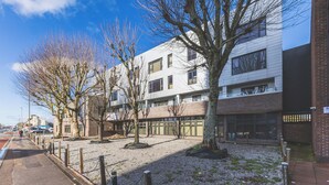 A modern building with multiple windows and a gravel courtyard. - Modern 1BDR Near Heathrow with Parking Amenities (Surrey)