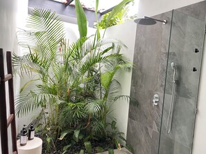 Une salle de bain moderne avec une douche à parois de verre, une petite composition florale et une porte en bois.