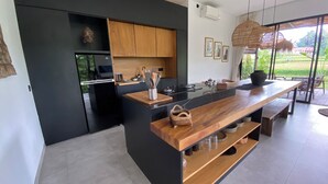 Een moderne keuken met een zwart houten kookeiland, roestvrijstalen apparatuur en uitzicht op de omgeving.