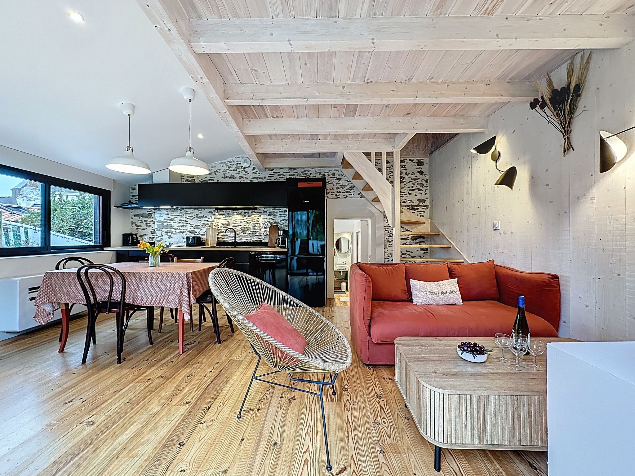 Eine moderne Küche mit Steinrückwand, Holzbalken an der Decke und einem Essbereich mit Tisch und Stühlen.