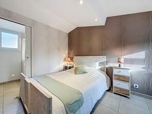 Ein Schlafzimmer mit Bett, Nachttischen, einem Schminktisch und einem Kleiderschrank, sowie einem Fenster.