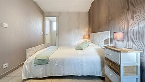 Et soveværelse med seng, natbord, lampe og et spejl.