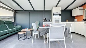 Et moderne køkken med spiseplads, en grøn sofa og et lille bord med frugt.