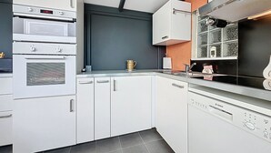 Et moderne køkken med hvide skabe, en Bosch opvaskemaskine og en indbygget ovn.