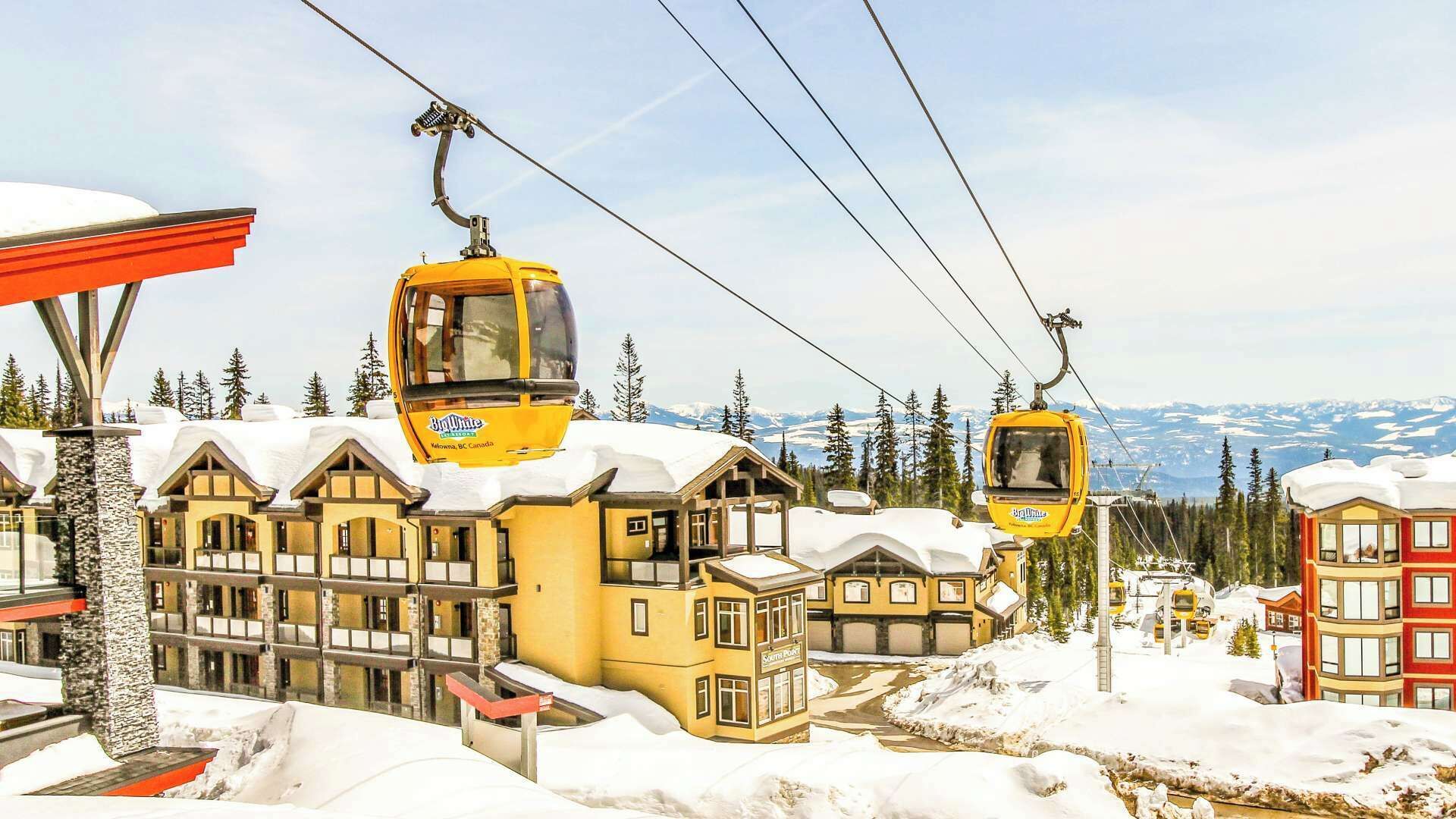 A ski resort with yellow cable cars, wooden buildings, and snowy surroundings.