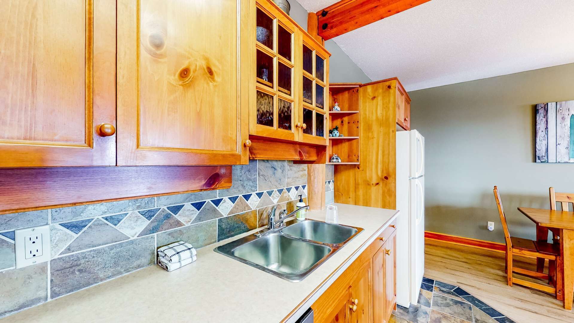 Eine Küche mit Holzausstattung, einem doppelten Waschbecken und einem Kühlschrank.