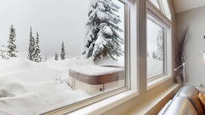 Una stanza con una grande finestra che si affaccia su un paesaggio innevato con alberi.