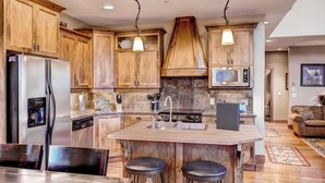 A modern kitchen with wooden cabinets, stainless steel appliances, and a central island with stools. - Okanagan - Snowbanks 4 (Beaverdell)