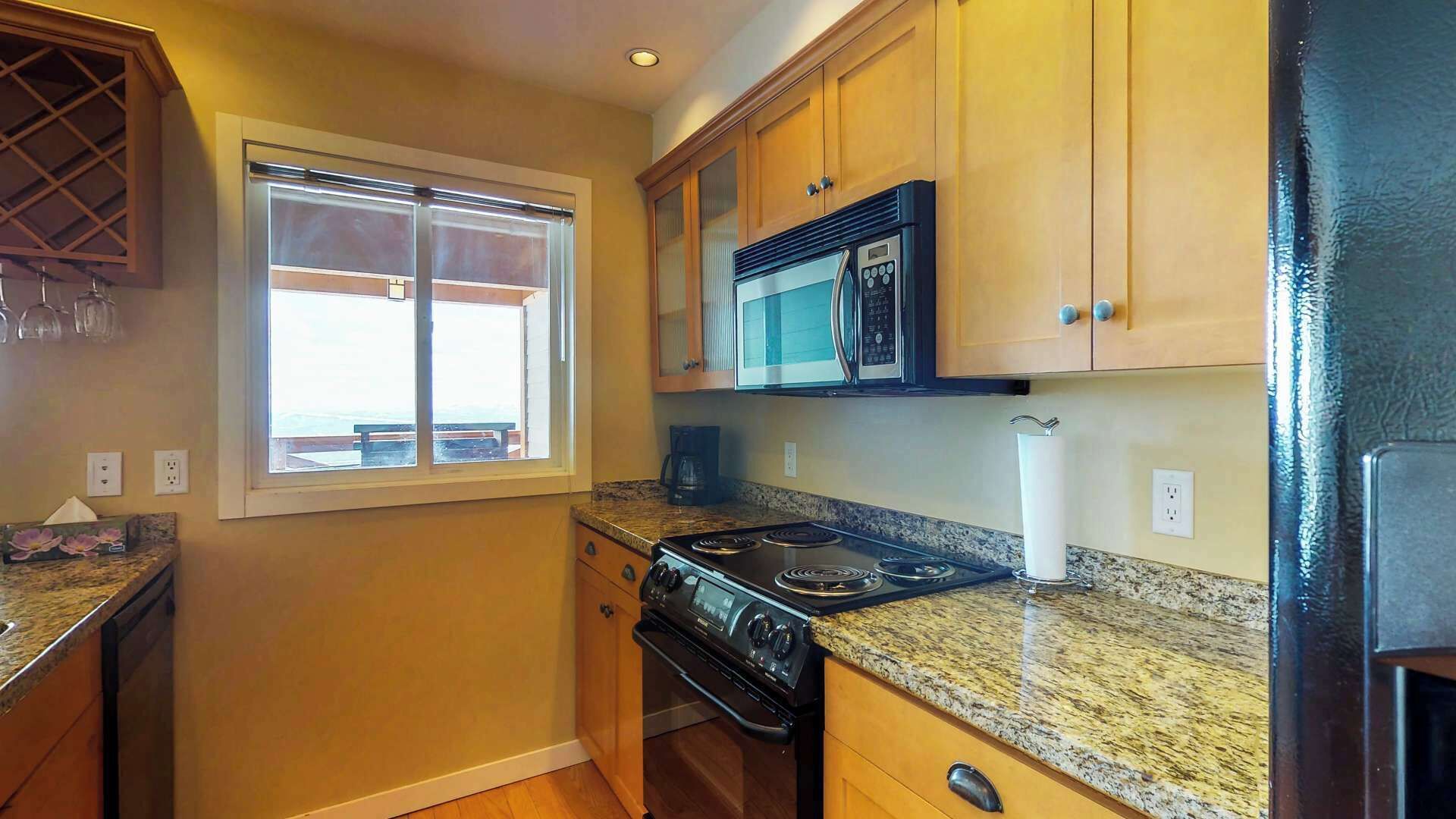 Una cocina compacta con estufa a gas, microondas y armarios de madera.