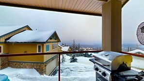 A balcony with a view of a snow-covered landscape, a stone wall, and a barbecue grill. - Okanagan - Tree Tops 10 (Big White Mountain)