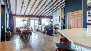 Ein großzügiger Wohnbereich mit Kamin, Holzboden und einem Essbereich mit einer Chandelier.