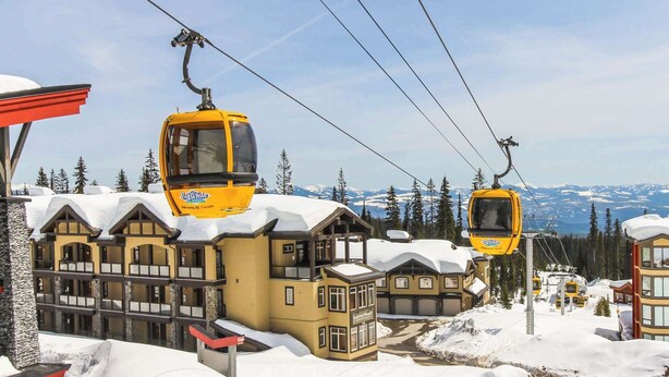 Ein Skigebiet mit einem großen Berghotel und zwei gelben Gondelbahnen.