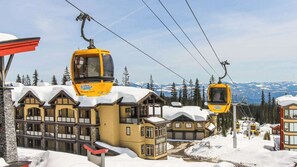 Een wintersportgebied met een ruim hotel en twee gele kabelbanen.