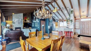 Een ruime woonkamer met een open haard, een houten eettafel en een keuken met een bar.