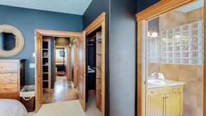 Een slaapkamer met een bed, een kaptafel en een inloopkast met een spiegel en planken.