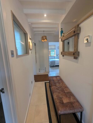 A hallway with a bench, a radiator, a mirror, and a door leading to a bedroom. - Stylish New Apartment in Central Seaview - 5 Star Comfort! (Seaview)