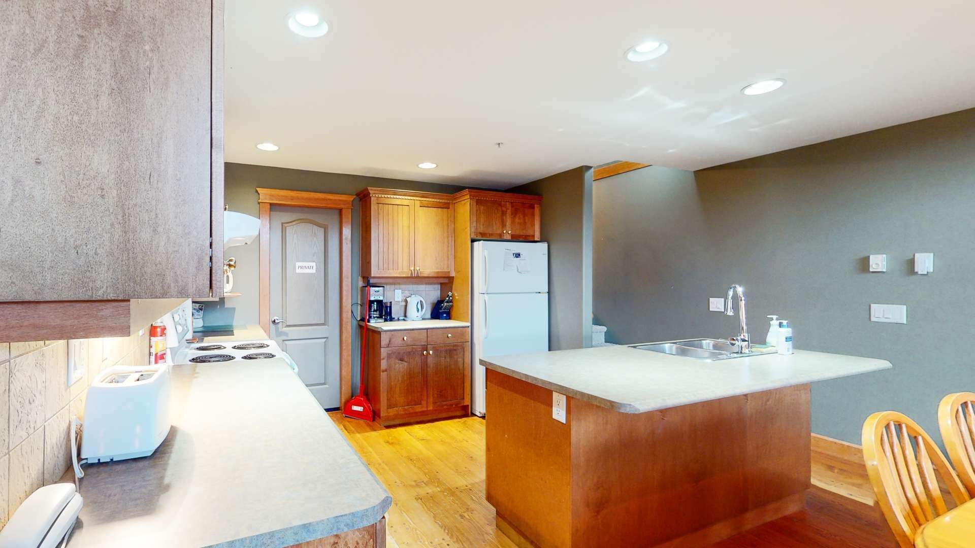 A compact kitchen with wooden cabinets, a built-in island, and a sink.