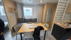 Ett kompakt bostadsutrymme med en matplats, en soffa och ett litet kök.