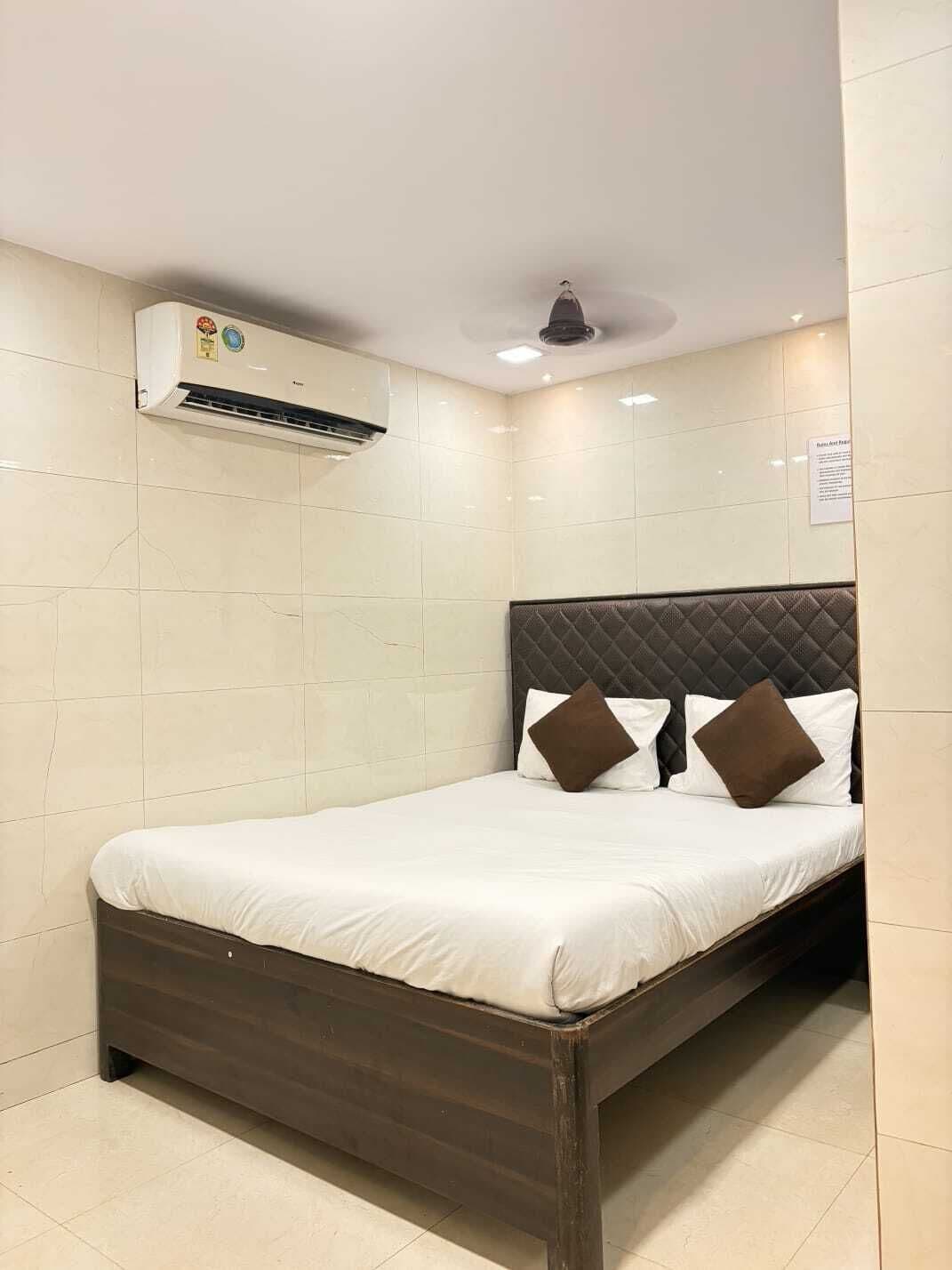 A hotel room with a bed, a ceiling fan, and an air conditioning unit.