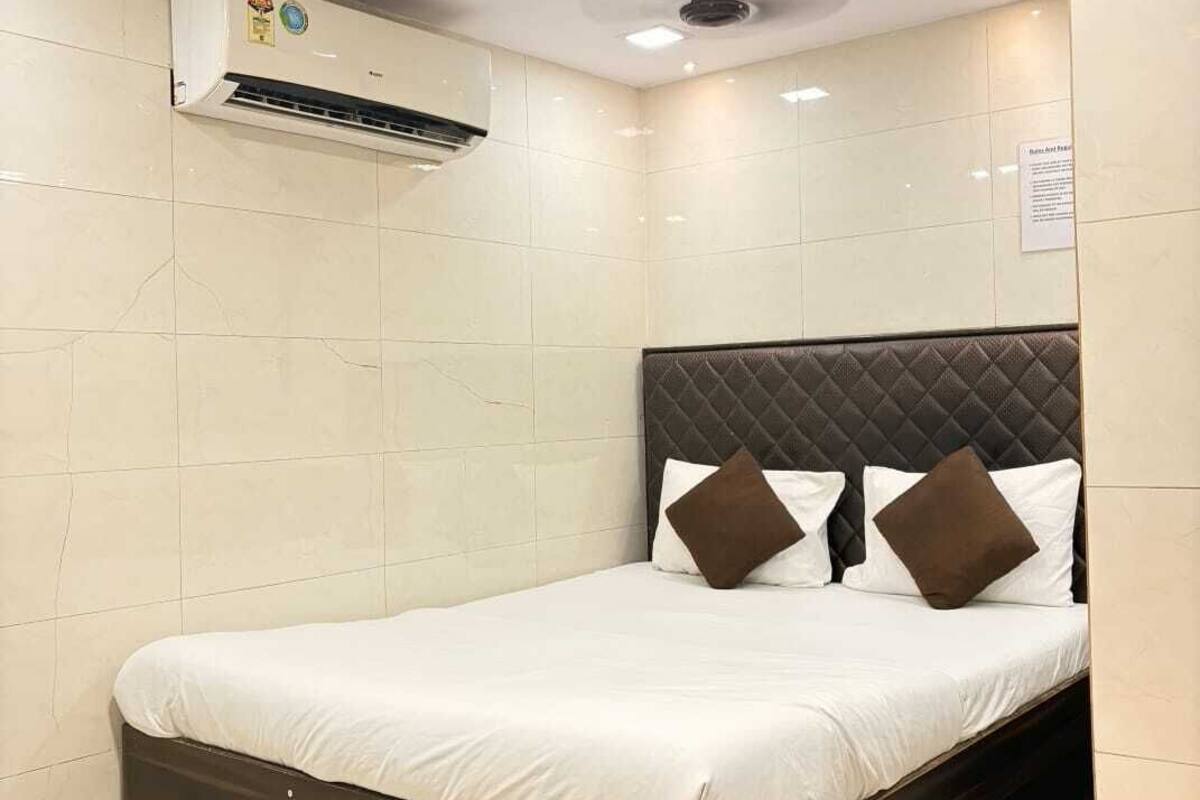 A hotel room with a bed, a ceiling fan, and an air conditioning unit.