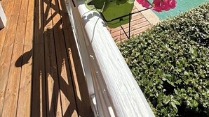 A wooden deck with a white railing, a garden with pink flowers, and a pool area with a gazebo. - Villa 5 stars Prestige Heated pool Biscarrosse Lac Golf for 6 persons (Biscarrosse)