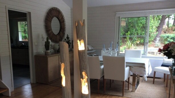 A dining area with a wooden table and chairs, a large mirror, and a view of greenery outside. - Villa 5 stars Prestige Heated pool Biscarrosse Lac Golf for 6 persons (Biscarrosse)
