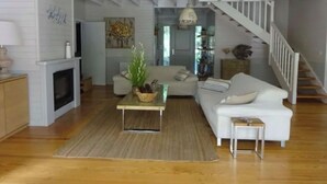 A spacious living room with a fireplace, a sofa, a coffee table, and a staircase leading to an upper level. - Villa 5 stars Prestige Heated pool Biscarrosse Lac Golf for 6 persons (Biscarrosse)