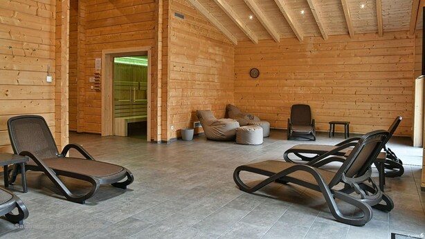 Un intérieur en bois avec des fauteuils confortables, un canapé et une horloge au mur.