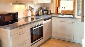Une cuisine de taille réduite équipée d’un four à micro-ondes, d’un four traditionnel, d’un évier et de placards.