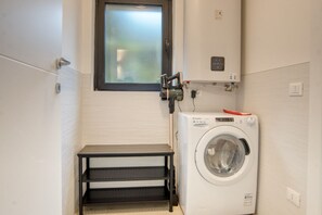 Ein kleiner Waschbereich mit Waschmaschine, Tisch und Fenster.