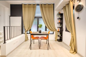 A dining area with a table set for two, a staircase, and a bookshelf with decorative items. - Hostmate - Milano - Suzzani - Bicocca (Milan)