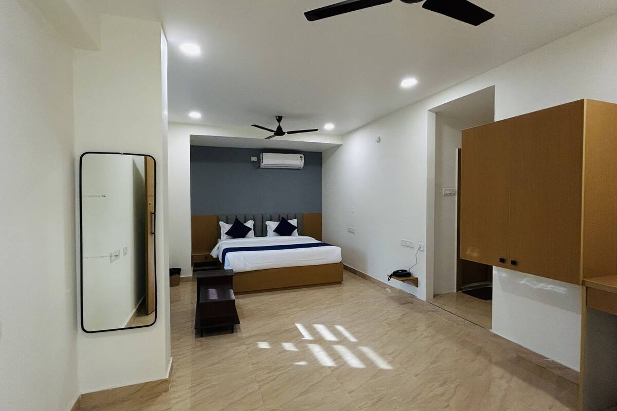 A modern bedroom with a bed, a ceiling fan, an air conditioning unit, and a wooden wardrobe.