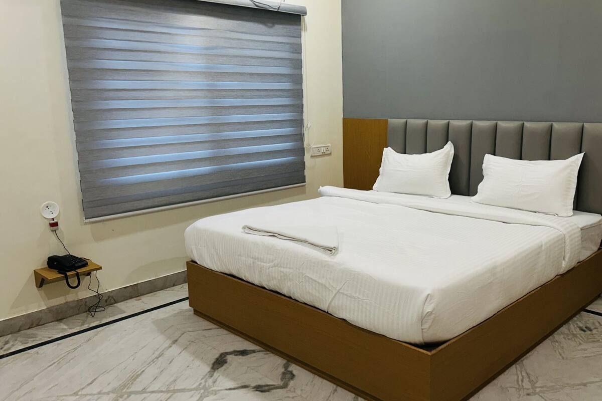 A neatly made bed with white linens in a hotel room.