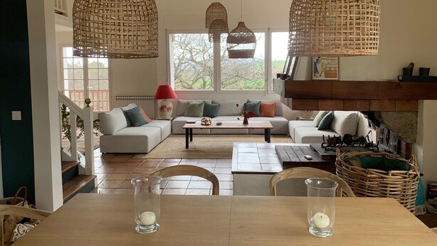 Een gezellige woonkamer met een zithoek, een salontafel en twee hangende rieten lampen.