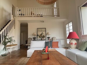 A spacious living room with a high ceiling, a staircase, and a large window. - Beautiful family home in the heart of the Basque countryside, less than 30 minutes from the beaches (ESPELETTE)