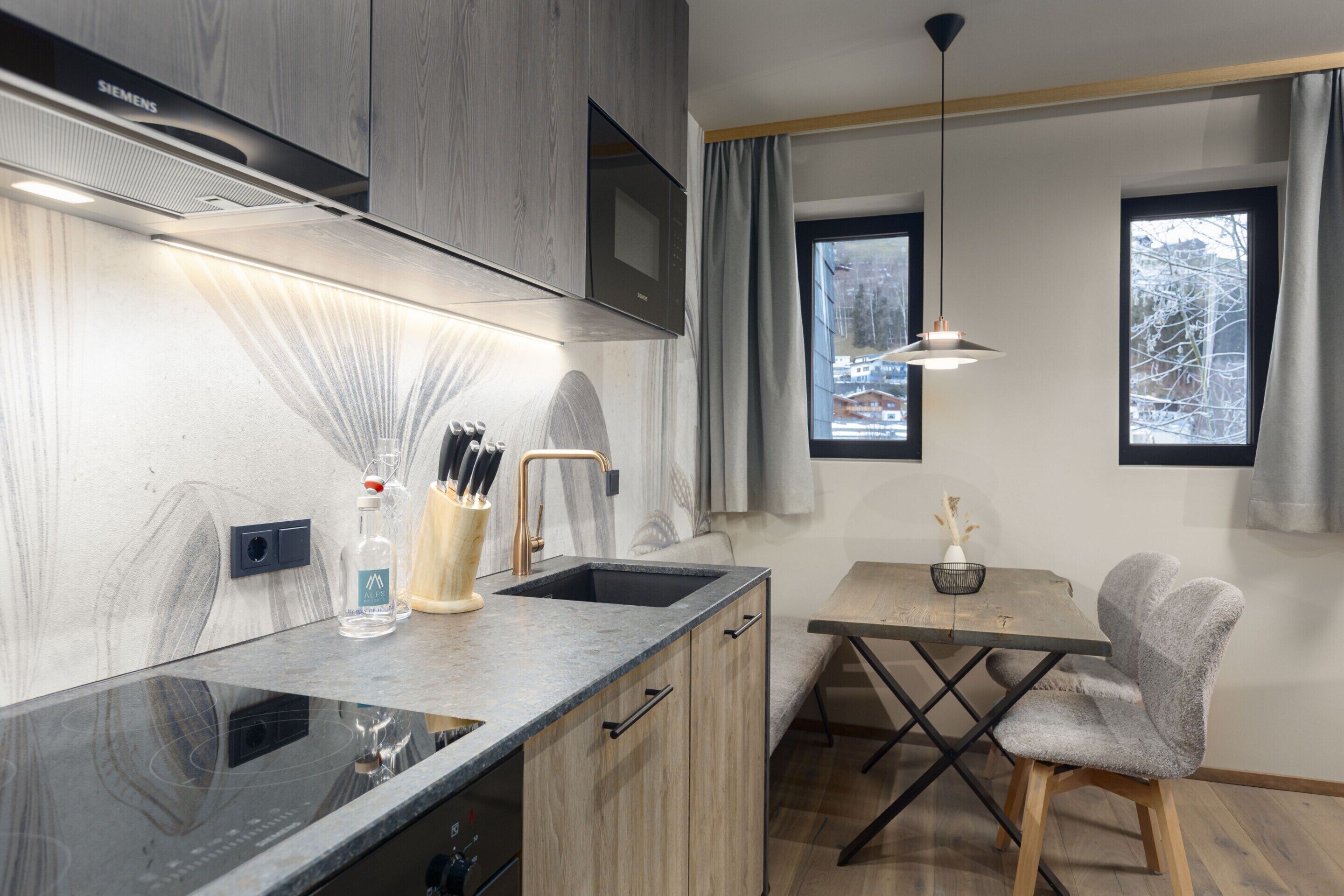 A modern kitchen with a built-in microwave, a sink, and a dining area with a table and chair.