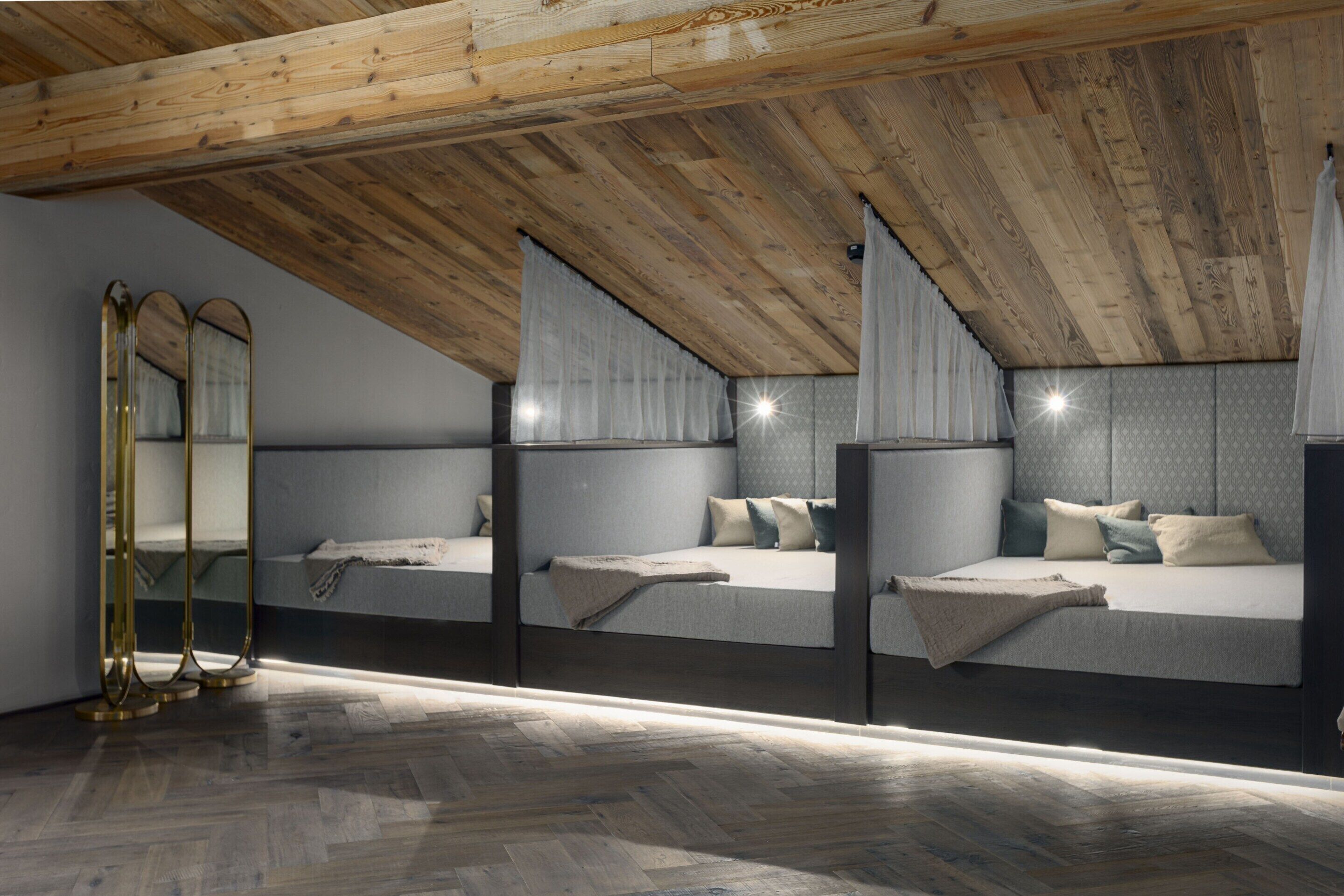 Une chambre avec un plafond en pente, une armoire à miroir et un plancher en bois.