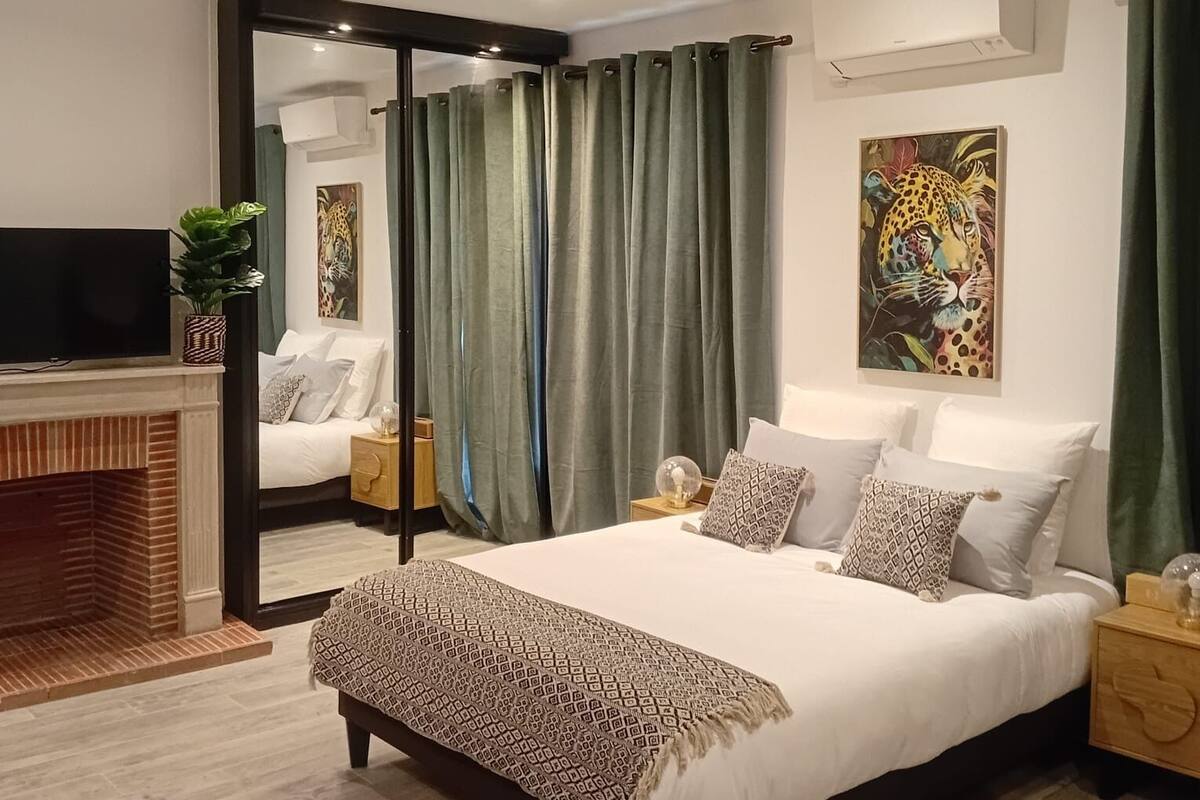 Une chambre moderne avec un grand lit, une télévision, une cheminée et un tableau au mur.
