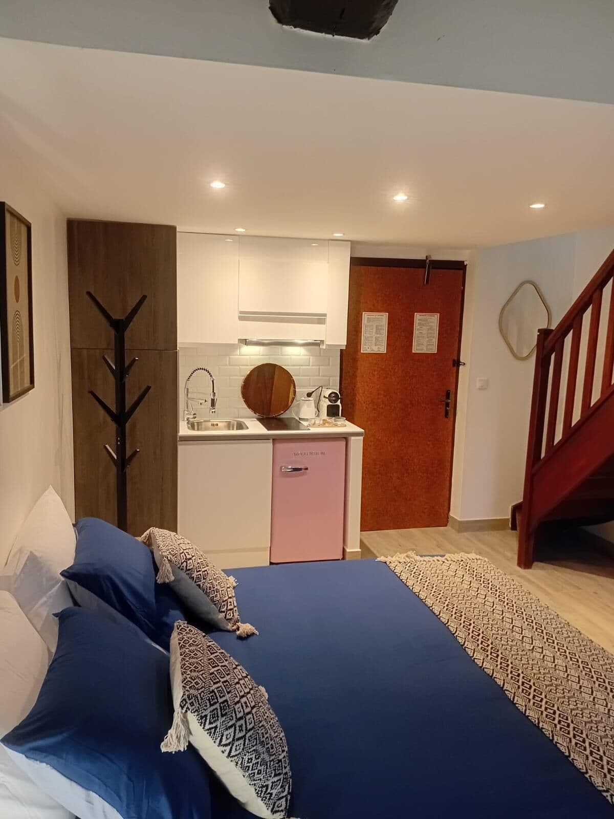 Un dormitorio pequeño con cama, una kitchenette y una escalera.