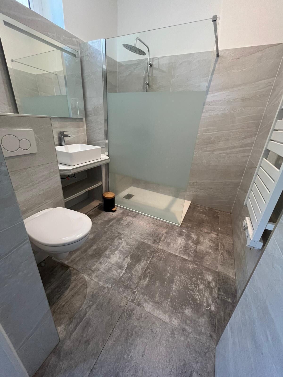 Ein modernes Badezimmer mit einer Duschkabine, einem weißen Waschbecken und einer Toilette.