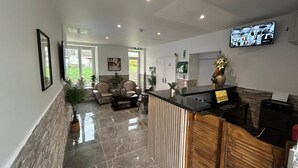 Un área de recepción con mostrador, zona de estar y un televisor mostrando varias tomas de cámara.